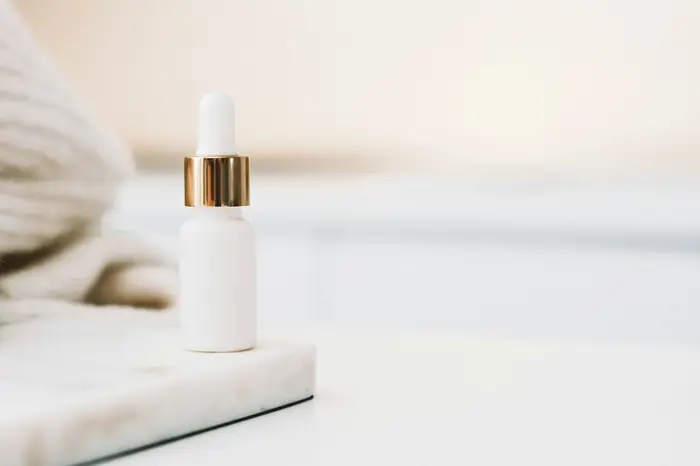 A white serum bottle resting on pale stone
