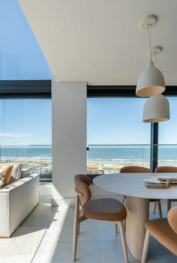 Pendant lights over a round dining table, looking out to sea